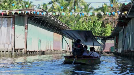 Back-view-of-a-pump-boat-with-tourists-moving-forward-in-Damnoen-Saduak-Floating-Market