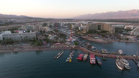 Eilat-hotel-strip-cityscape-over-the-Red-Sea-at-sunset,-Drone-footage