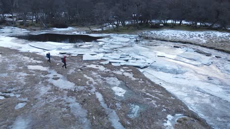 Couple-of-travelers-walking-towards-a-river-with-blocks-of-ice