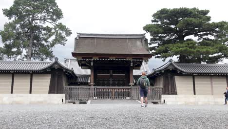 Tourist-walking-towards-the-massive-wooden-gate-at-Kyoto-imperial-palace---wide-angle-perspective