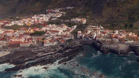 Pueblo-Pesquero-De-Garachico-En-Canarias,-Rodeado-Por-Su-Mar-Y-Custodiado-Por-Su-Gran-Iglesia-Catolica,-Toma-Aerea-Desde-Un-Drone-A-4k-60-Fps---02