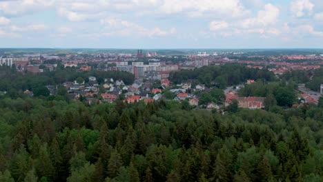 Wide-aerial-dolly-left-showing-city-Eskilstuna-from-afar-with-lush-forrest-in-foreground