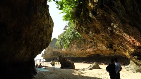 Entrance-to-Suluban-beach-on-Bali-Indonesia-with-sand-and-people-between-two-cliffs-on-a-sunny-day-full-of-surfers-and-green-vines