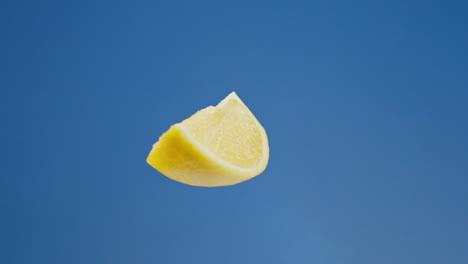 Zitronenscheibe-Oder--keil-In-Schwebender-Rotation-Vor-Blauem-Hintergrund