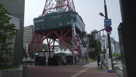 Ground-Level-Of-Sapporo-TV-Tower-With-Pedestrians-And-Cars-On-The-Street-In-Sapporo,-Hokkaido,-Japan