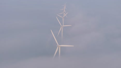 Windturbines-spinning-with-low-clouds-at-Friesland-during-sunrise,-aerial
