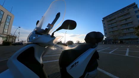 Slow-Motion-Footage-Moving-Away-from-a-Scooter-Standing-in-a-Parking-Lot-in-Italy