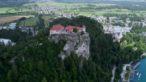 Cinematic-drone-flight-over-castle-with-lake-and-city-of-Bled-in-the-valley-during-summer-day-in-Slovenia