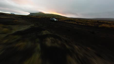 FPV-Drohne-Fliegt-Bei-Sonnenuntergang-An-Einem-Geländewagen-Vorbei-Durch-Die-Kahle-Isländische-Landschaft