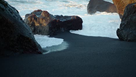 Kalter-Meeresschaum-Prallt-Gegen-Einen-Felsen-Am-Schwarzen-Sandstrand-In-Island