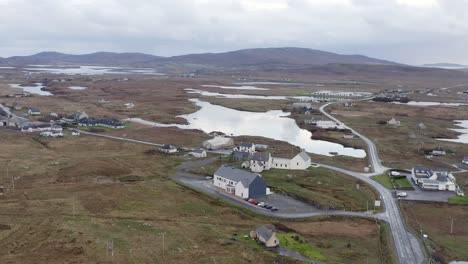 Moving-drone-shot-of-the-Cnoc-Soilleir-building-and-the-village-of-Daliburgh-in-South-Uist,-part-of-the-Outer-Hebrides-of-Scotland