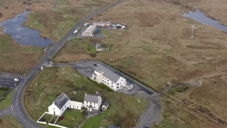 Tilting-drone-shot-featuring-the-Cnoc-Soilleir-building-near-Lochboisdale-in-South-Uist,-then-tilting-to-face-northward-towards-North-Uist