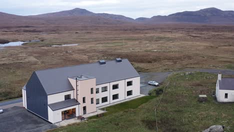 Static-drone-shot-of-the-Cnoc-Soiller-building-and-the-surrounding-moorland-and-peatland-on-the-island-of-South-Uist,-part-of-the-Outer-Hebrides-of-Scotland