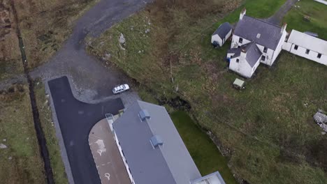 Absteigende-Und-Kippbare-Drohnenaufnahme-Des-Cnoc-Soiller-Gebäudes-Und-Des-Dorfes-Daliburgh-In-Süd-Uist,-Teil-Der-Äußeren-Hebriden-Schottlands