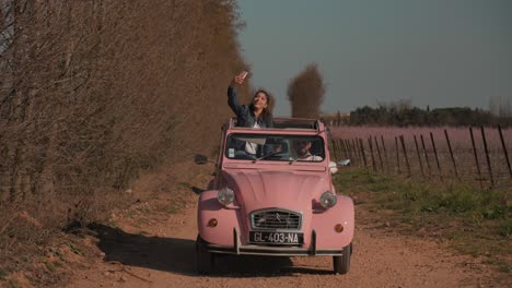 Slow-motion-shot-of-a-female-standing-in-a-Deux-Chevaux-taking-a-selfie-in-Camargue