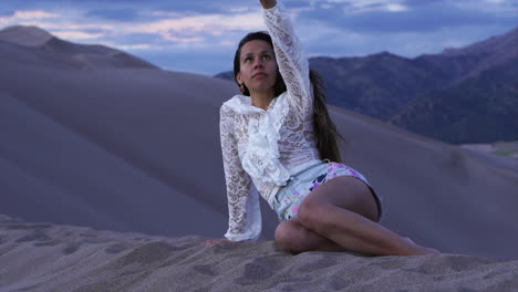 Weibliche-Frauen,-Schauspielerin,-Model,-Die-Auf-Colorado-Liegt,-Der-Great-Sand-Dunes-National-Park,-Sand-Aufsammelt,-Der-Im-Wind-Weht,-Malerische-Berglandschaft,-Abenddämmerung,-Lila,-Abenteuer,-Rocky-Mountains,-Stille,-Bewegung