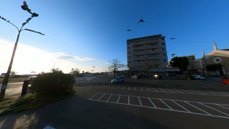 A-Multitude-of-Birds-Flies-Over-a-Parking-Lot-in-Rimini,-Italy