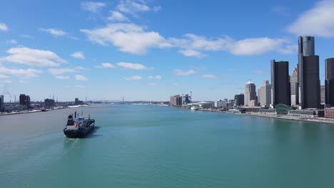 Cargo-ship-sailing-near-majestic-skyline-of-Detroit,-aerial-drone-view