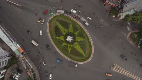 Busy-traffic-roundabout-hyperlapse-or-time-lapse-from-top-down-aerial-view-with-star-shaped-garden-in-its-center-during-the-day