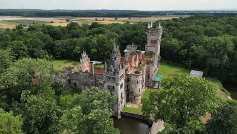 Tilt-up-shot-of-old-castle-in-the-middle-of-the-forest,-Kopice,-Poland