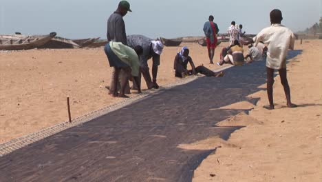 Grupo-De-Pescadores-Nigerianos-Reparando-Su-Red-En-La-Playa