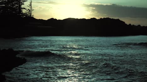 Stimmungsvolle-Wellen,-Die-Bei-Sonnenuntergang-In-Zeitlupe-Weit-Und-Stimmungsvoll-Gegen-Felsen-Prallen