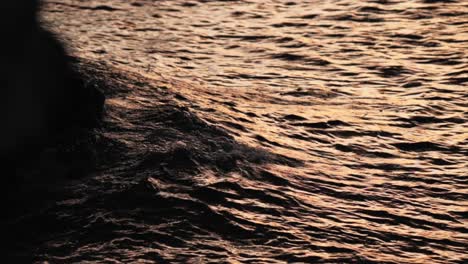 Moody-waves-crashing-into-rocks-at-sunset-in-slow-motion-close-up