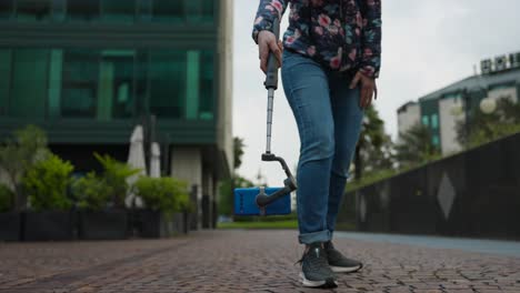 Woman-uses-telescopic-extendable-gimbal-stabilizer-with-mobile-phone-mounted-to-shoot-at-floor-level