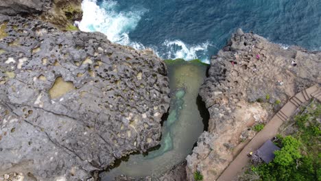 Aerial-bird's-eye-view-of-Angel-Billabong-on-Nusa-Penida-island,-a-tidal-infinity-rock-pool-amid-naturally-formed-patterns-and-texture-of-jagged-formations