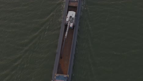 Close-up-shot-of-cargo-ship-full-of-sand-on-ijsselmeer-during-sunset,-aerial