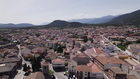 Aerial-flyover-of-typical-Spanish-village,-nestled-in-valley,-mountain-backdrop