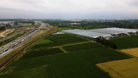 Industrial-buildings-and-truck-traffic-jam-in-highway-road,-aerial-view