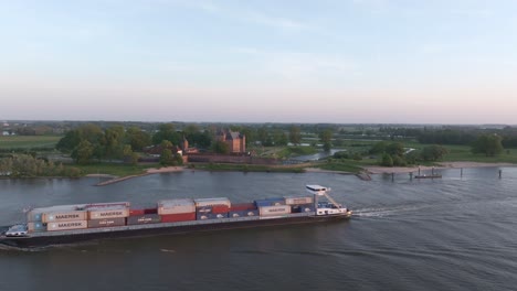 Containerschiff-Auf-Dem-Fluss-Waal,-Vorbei-An-Schloss-Loevestein,-Luftaufnahme