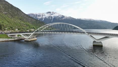 The-Loftesnes-bridge-in-Sogndal-Norway---Low-altitude-aerial-presenting-bridge-from-seaside-with-scenic-mountain-background