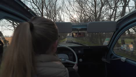 POV-shot-of-beautiful-Caucasian-woman-excitedly-driving-2CV-open-roof-car-in-countryside