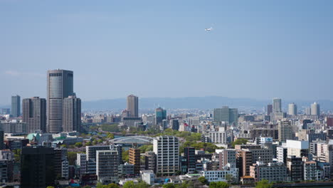 Slow-motion-shot-of-a-commercial-airplane-flying-over-downtown-Osaka,-Japan