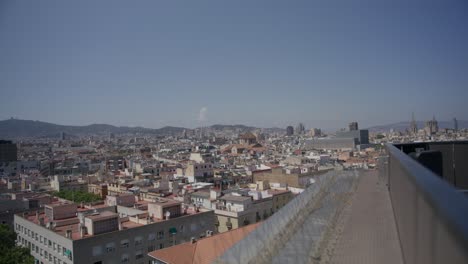 Vista-De-La-Cornisa-Del-Edificio,-Visión-General-De-Barcelona-España-Temprano-En-La-Mañana-Mientras-Los-Pájaros-Vuelan-A-Lo-Largo-Del-Horizonte-De-La-Ciudad-En-6k