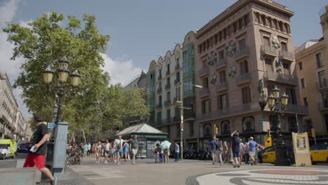 Cerca-De-Grandes-Multitudes-De-Turistas-Caminando-Cerca-De-Edificios-Altos-A-Lo-Largo-De-Calles-Concurridas-Al-Atardecer-En-Barcelona-España-En-6k
