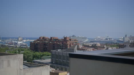 Gebäudevorsprung-Mit-Blick-Auf-Den-Hafen,-Überblick-über-Barcelona,-Spanien-Am-Frühen-Morgen,-Während-Vögel-In-6-Km-Entfernung-Entlang-Der-Skyline-Der-Stadt-Fliegen