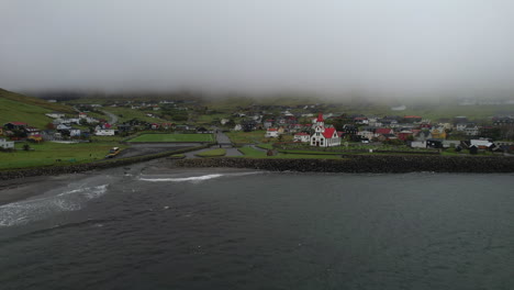 Sandavagur-village,-Vagar-island:-aerial-view-traveling-in-to-the-village-and-church-on-the-Faroe-Islands