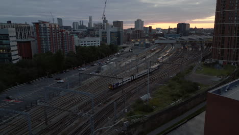 Establishing-Drone-Shot-Over-Leeds-Train-Station-at-Sunrise-with-Train-Departing-in-Leeds-City-Centre