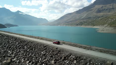 Mont-Cenis-mountain-road-with-car-driving-along-lake-coast,-France