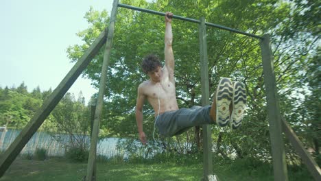 Topless-young-man-performs-a-Hanging-L-sit-exercise-outdoors