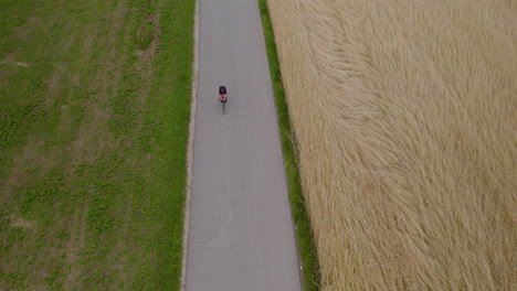 Wide-shot-of-cyclist-race-in-country-road-next-to-farm-fields
