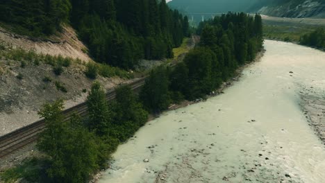 Aerial-view-over-the-Kicking-Horse-river-and-railway-tracks-in-BC,-Canada---Hazy-sky-due-to-wildfire-smoke