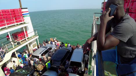 Tilt-down-shot-of-people-and-vehicles-inside-Kunta-Kinteh-ferry-sailing-from-Banjul-to-Barra-in-Gambia-on-a-sunny-day