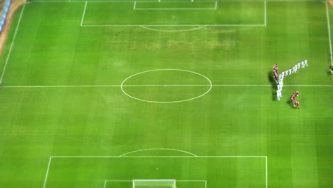 Aerial-drone-shot-of-a-football-match-on-a-green-field,-with-a-tilt-shift-effect