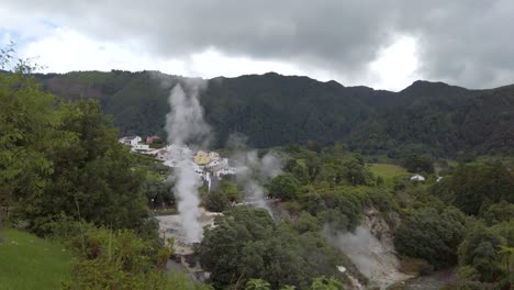 Top-view-of-the-active-geysers-and-fuming-hot-springs-at-natural-landmark-"Caldeiras-das-Furnas"-in-Furnas,-San-Miguel-Island,-Azores,-Portugal-with-hortensia-flowers-in-the-foreground