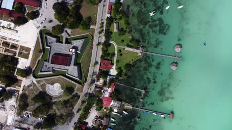 drone-eye-bird-view-above-san-Felipe-castle-in-Bacalar-Quintana-Roo-state-Mexico-with-blue-water-lagoon-and-holiday-resort-on-tropical-beach