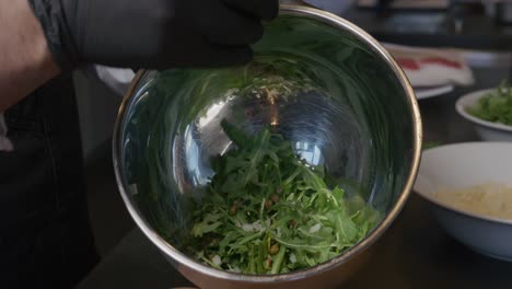 Onions-are-added-to-a-bowl-of-fresh-arugula,-contributing-to-a-vibrant-salad